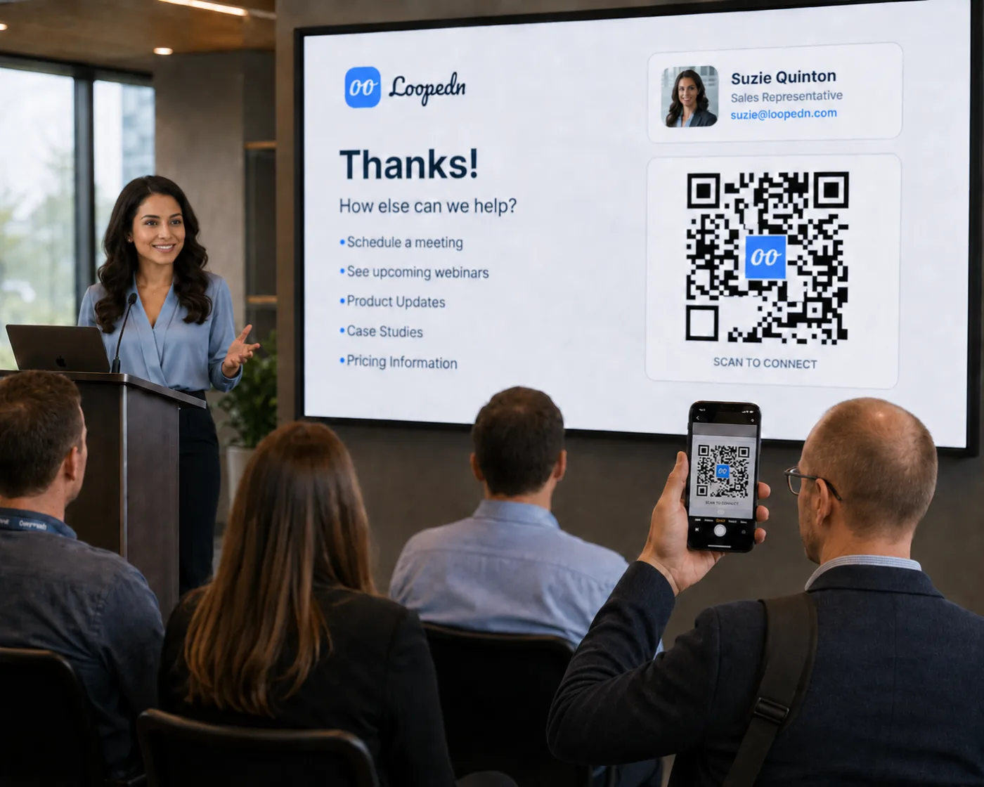 A rep presenting at a session, with an attendee scanning the Loopedn QR code off the screen to receive a personalized follow-up