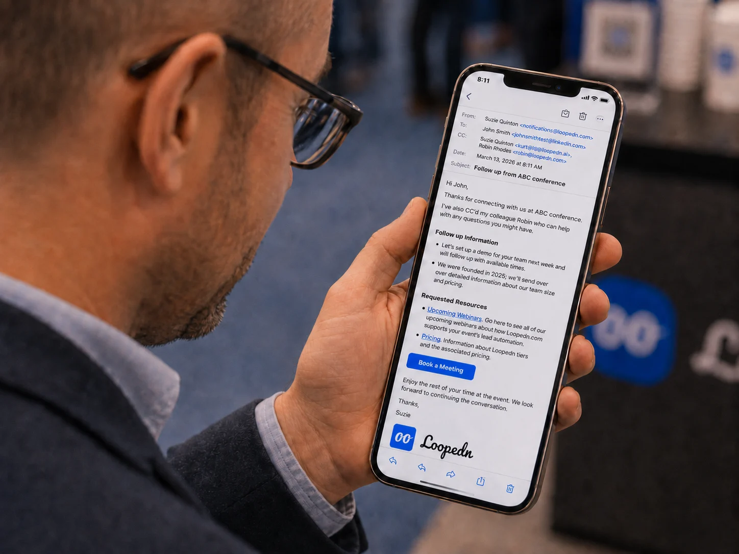 Attendee reading a personalized Loopedn follow-up email on their phone, with a Book a Meeting button